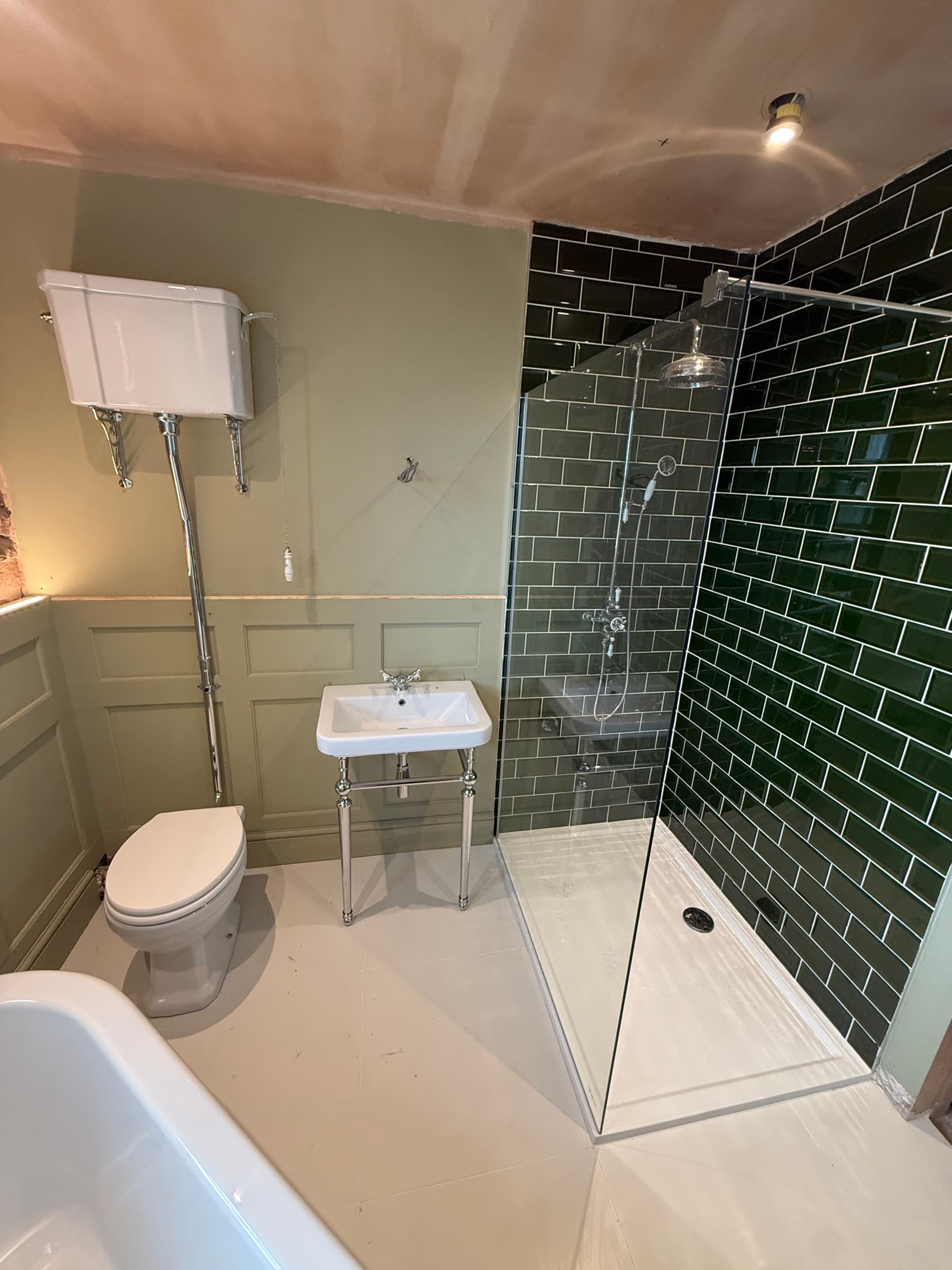 Finished bathroom with a walk-in shower, dark green metro tiles and traditional sanitaryware